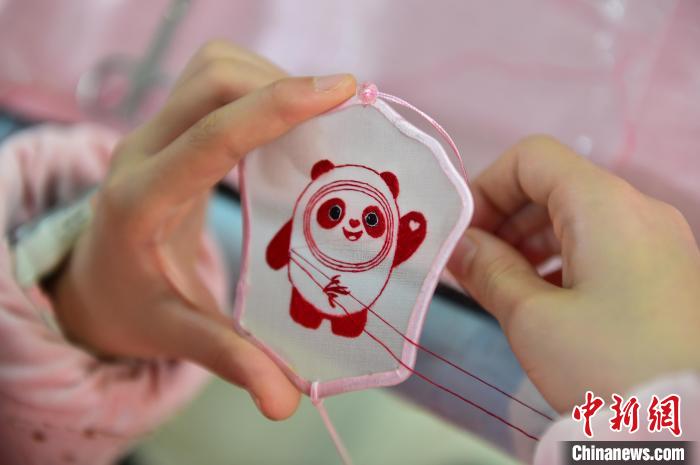 圖為一名小學(xué)生正在繡制2022年北京冬奧會吉祥物“冰墩墩”形象。　喻云亮 攝