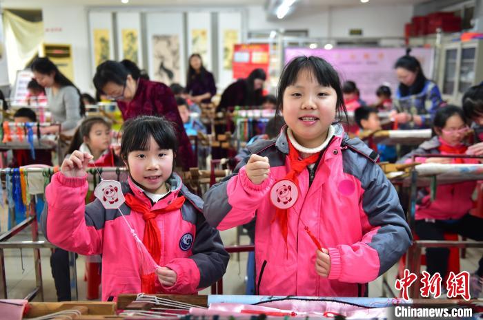 圖為小學(xué)生展示繡制好的2022年北京冬奧會吉祥物“冰墩墩”形象。　喻云亮 攝