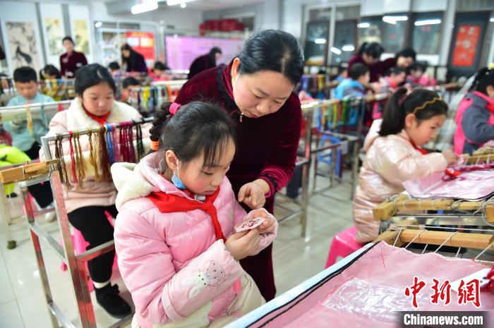 江西省級非遺豫章繡傳承人手把手指導(dǎo)小學(xué)生繡制2022年北京冬奧會吉祥物“冰墩墩”形象。　喻云亮 攝