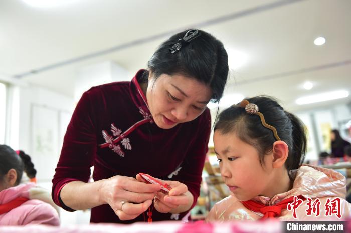 江西省級非遺豫章繡傳承人手把手指導(dǎo)小學(xué)生繡制2022年北京冬奧會吉祥物“冰墩墩”形象。　喻云亮 攝