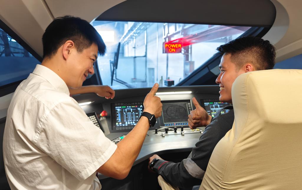 8月25日，在印度尼西亞萬隆的雅萬高鐵德卡魯爾動(dòng)車所內(nèi)，中國師傅穆振（左）在向印尼火車司機(jī)塞蒂亞萬講解動(dòng)車組出庫前的上電作業(yè)。