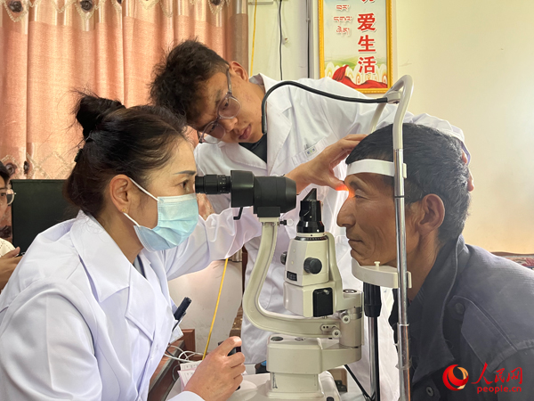 王紅英（左）和團隊成員為達熱村村民檢查眼睛。人民網記者 杜燕飛攝