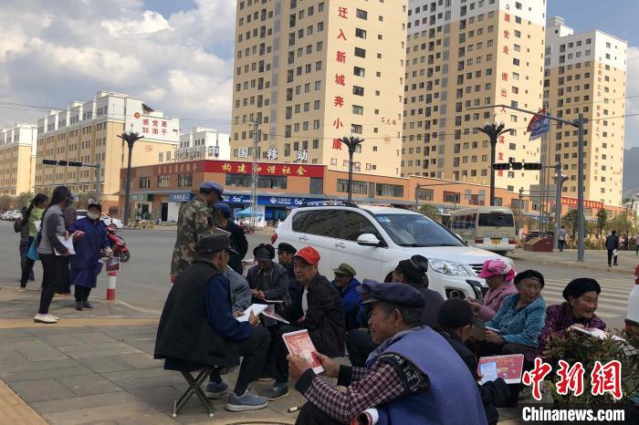 圖為會澤縣城易地扶貧搬遷安置點(diǎn)內(nèi)，老人們聚在廣場上聊天，身后是他們的新家。　繆超 攝