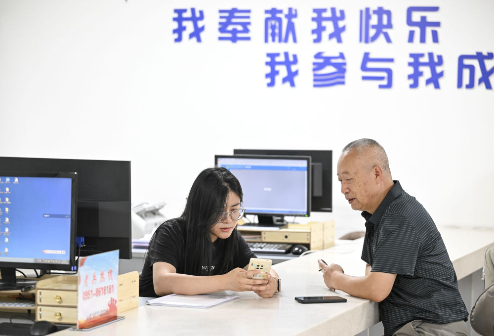 2024年6月20日，在寧夏銀川市金鳳區長城花園社區黨群服務中心，工作人員幫助居民辦理業務。圖片來源 新華社