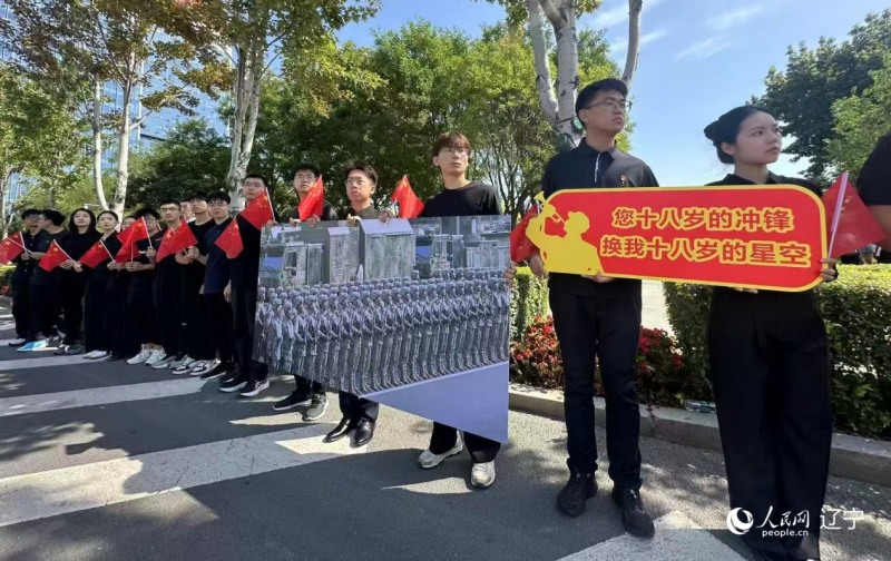 沈陽市人民廣場上，大學生們手持閱兵的圖片，告慰英烈。人民網記者 周頌雪攝