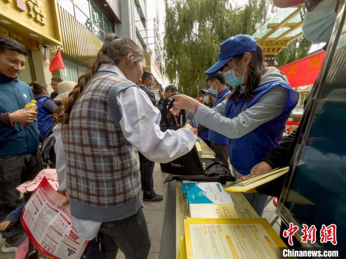 圖為志愿者為市民發(fā)放網絡安全宣傳手冊。　謝牧 攝