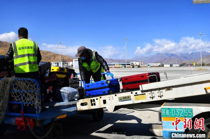 圖為機(jī)場工作人員傳送旅客行李箱。　周航 攝