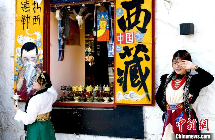 4月17日，游客身著藏式元素服裝在拉薩八廓街拍照留念。　李林 攝